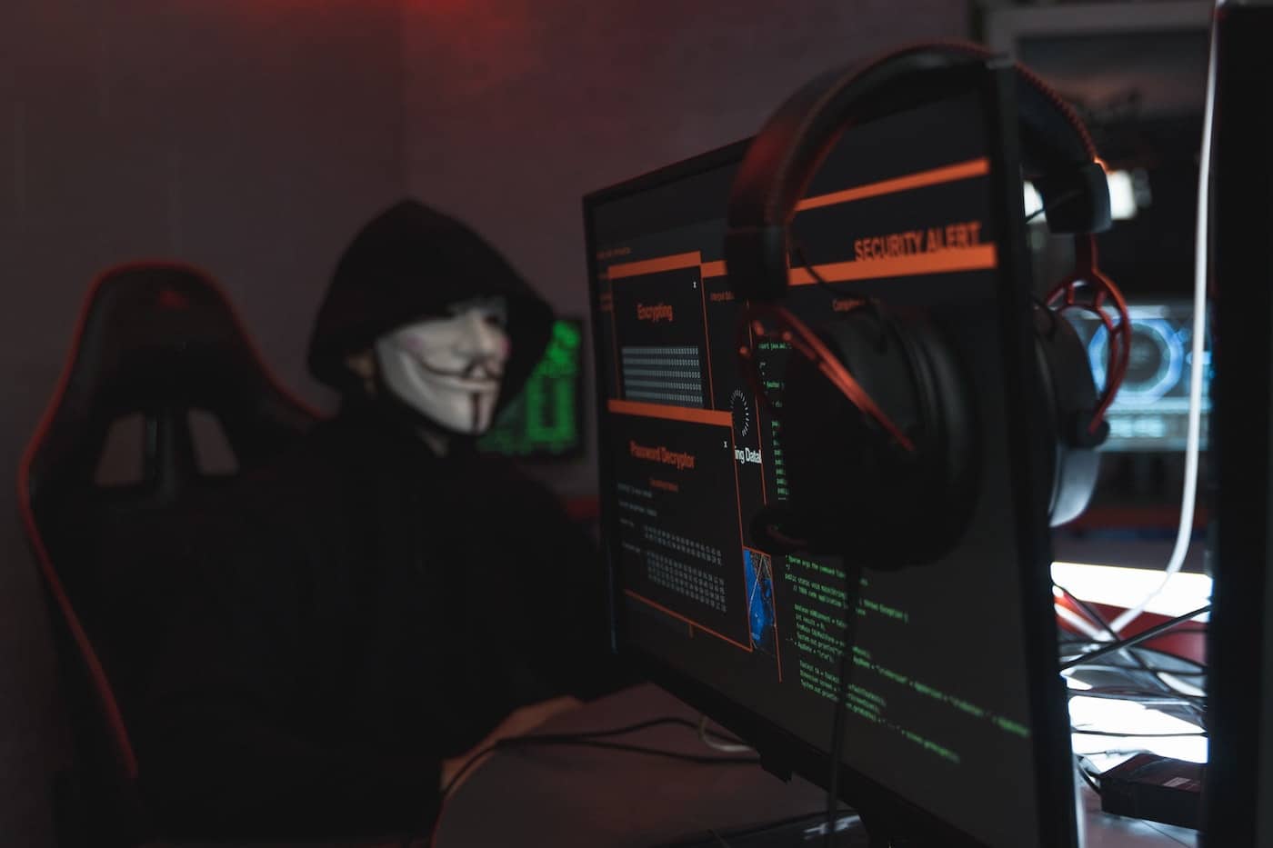 Image of hacker wearing a mask sitting behind a computer. Meant to symbolize social engineering attacks.