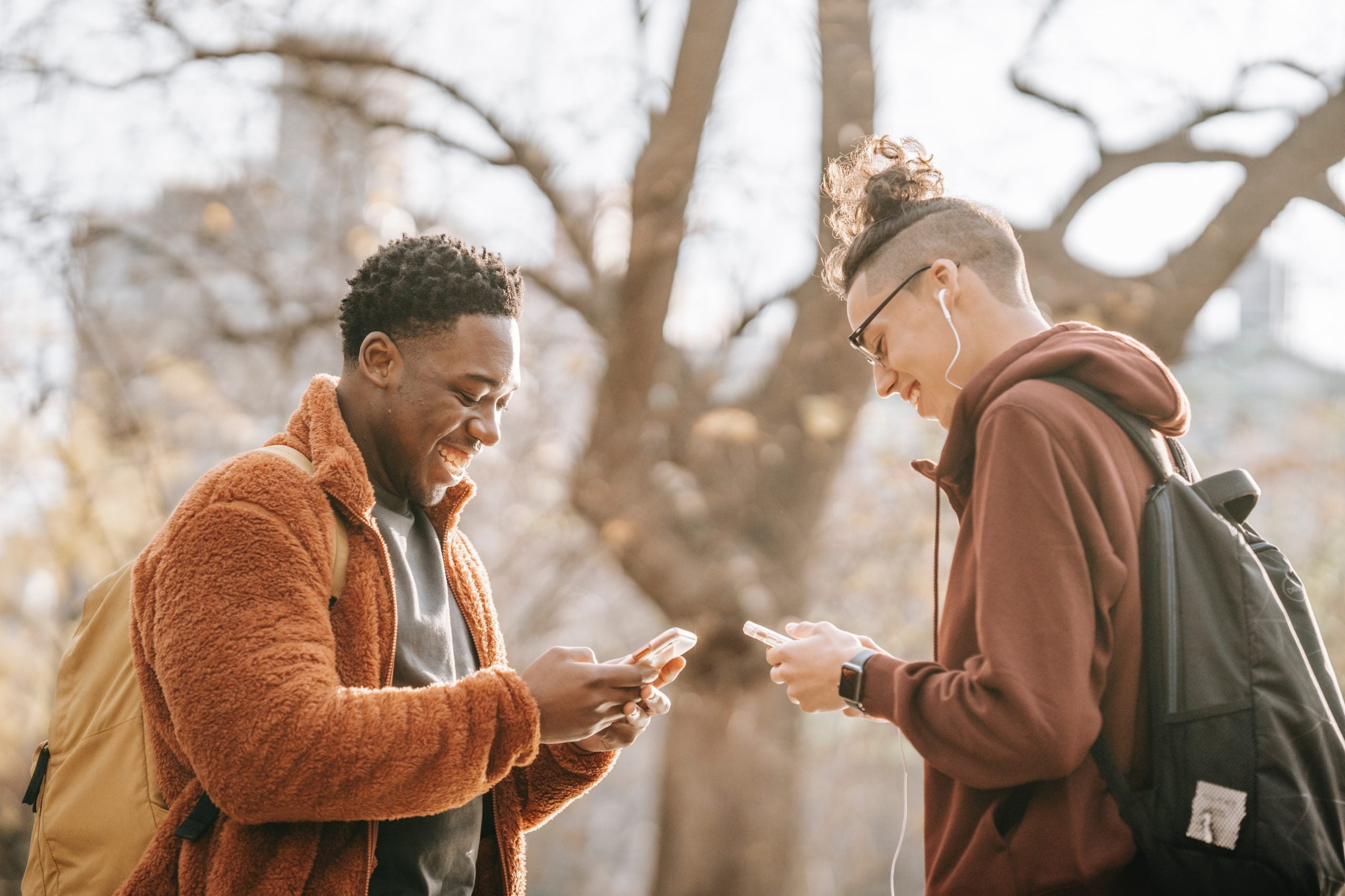 A picture of two friends sharing contact details on their phones as this article is about the Top Twitter accounts to follow for cybersecurity expertise, news, and the latest commentary.